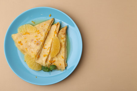 Plate with tasty crepes Suzette on beige table, top view. Space for textの写真素材