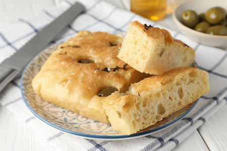 Slices of delicious focaccia bread with olives, thyme and salt on white wooden table, closeupの写真素材