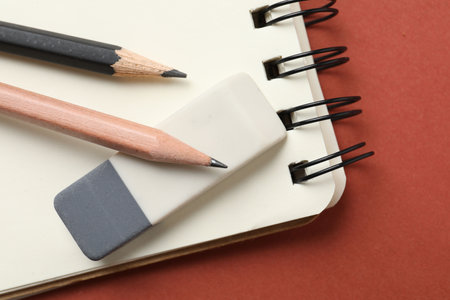 Eraser, pencils and notebook on brown background, top viewの写真素材