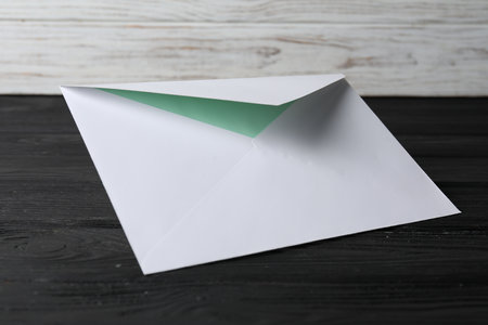 Paper envelope with letter on black wooden table. Mockup for designの写真素材