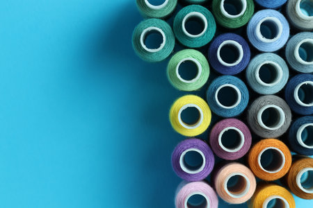 Spools of colorful sewing threads on light blue background, flat lay. Space for textの写真素材