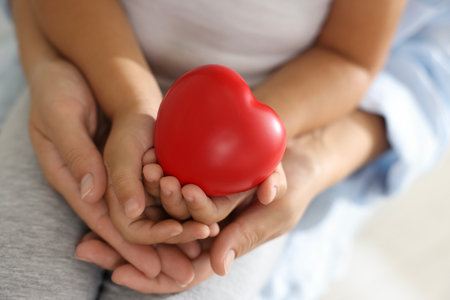 Little girl and her mother with red heart figure indoors, closeupの写真素材