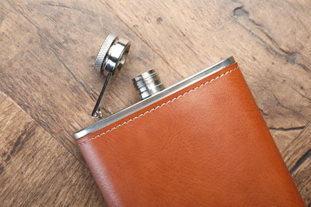 One hip flask on wooden table, top view