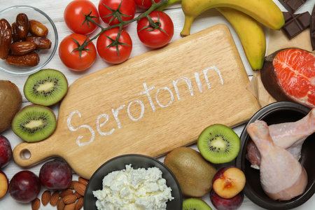 Wooden board with word Serotonin and different fresh products on white table, flat layの写真素材