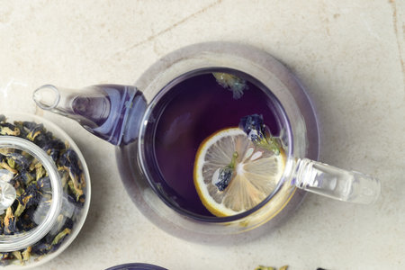Delicious butterfly pea flower tea with lemon on gray textured table, flat layの写真素材