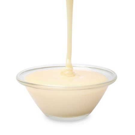 Pouring condensed milk into bowl isolated on whiteの写真素材