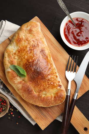 Delicious fresh calzone pizza served on wooden table, flat layの写真素材