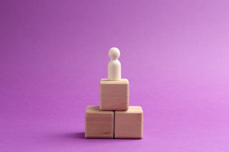 Human figure on wooden cubes against violet background. Competition conceptの写真素材