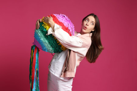 Emotional woman with colorful pinata on pink backgroundの写真素材