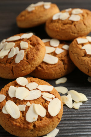 Tasty cookies with almond flakes on wooden table, closeup