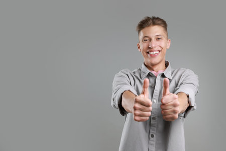 Happy man showing thumbs up on gray background, space for text. Like gestureの写真素材