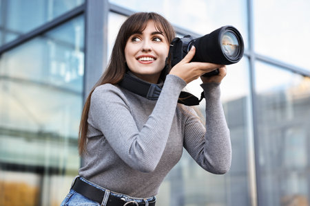 Professional photographer with digital camera near building outdoors, low angle viewの写真素材