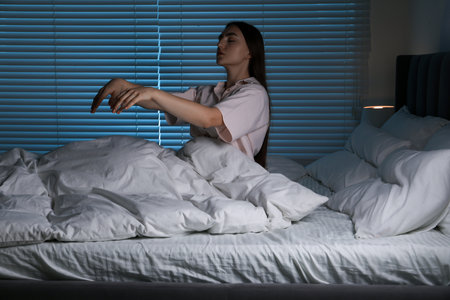 Young woman suffering from sleepwalking on bed at homeの写真素材