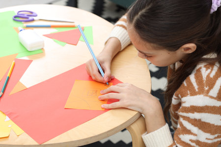 Girl drawing card at table indoors. Art and craft