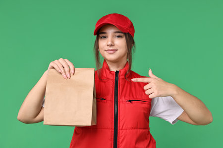 Girl in uniform with paper bag on green background. Work for teenagersの写真素材
