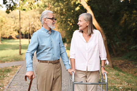 Senior couple with walking frame and cane in parkの写真素材