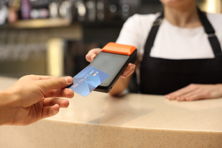 Man paying with credit card via terminal in cafe, closeup