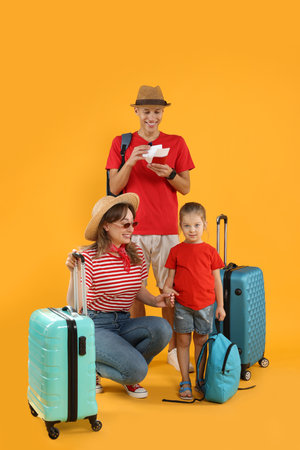 Travellers with suitcases and backpack. Happy family on yellow backgroundの写真素材
