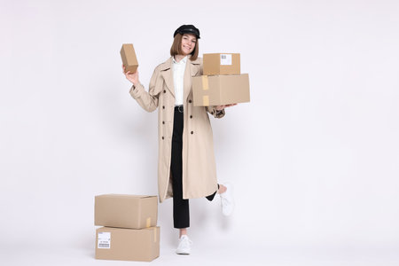 Happy postwoman with parcels on white background