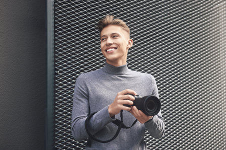 Professional photographer with modern camera near wall outdoorsの写真素材