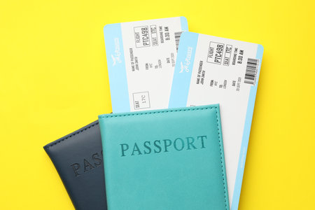Travel agency. Flight tickets and passports on yellow background, top viewの写真素材