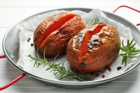 Tasty cooked sweet potatoes with rosemary on white wooden table, closeupの写真素材