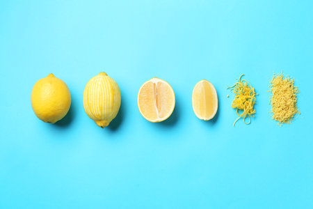 Lemon zest, whole and cut fresh fruits on light blue background, flat lay