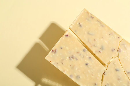 Pieces of tasty white chocolate on beige background, top view. Space for text