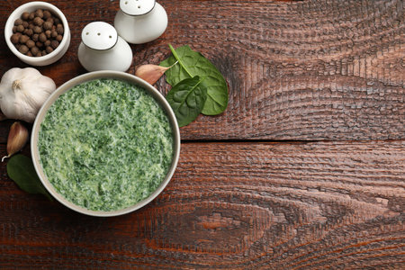 Delicious spinach sauce served on wooden table, flat lay. Space for textの写真素材