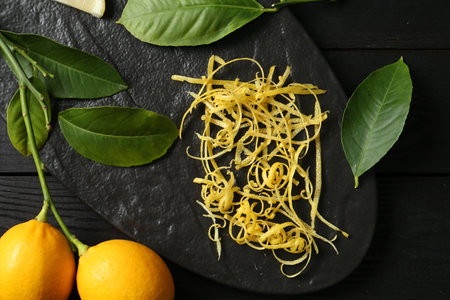 Lemon zest, fresh fruits and leaves on black wooden table, top viewの写真素材