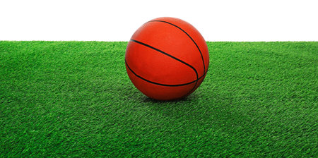 One basketball ball on green grass against white background. Sport equipmentの写真素材