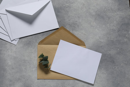 Paper envelopes with letter and eucalyptus branch on gray textured background, flat lay. Mockup for designの写真素材