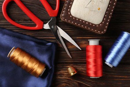 Different sewing supplies on wooden table, flat lay