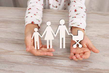 Adoption Little girl with figures of family at wooden table, closeupの写真素材