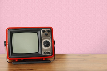 Retro TV on wooden table near wall with vintage style wallpaper. Space for textの写真素材