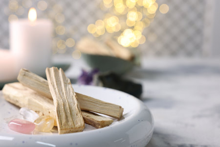 Palo santo sticks, gemstones and burning candle on light gray table, closeup. Space for textの写真素材