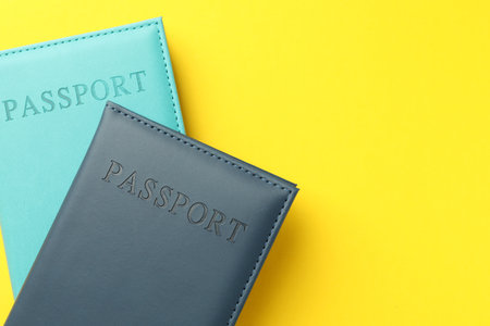 Passports in color covers on yellow background, top view. Space for textの写真素材