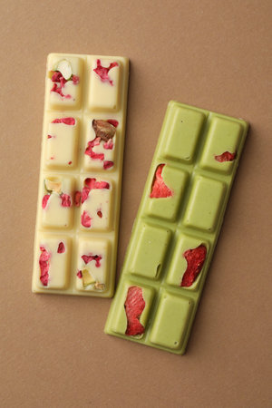 Different chocolate bars on beige background, top view