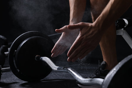 Man clapping hands with talcum powder before training with barbell in gym, closeupの写真素材