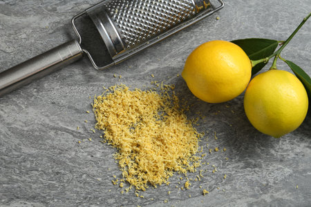 Lemon zest, grater and fresh fruits on gray textured table, flat layの写真素材
