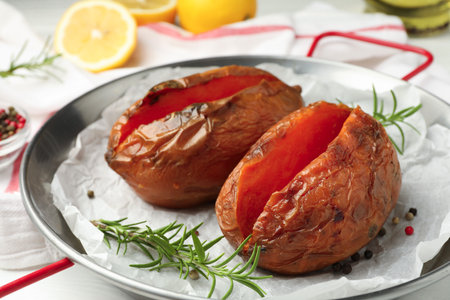 Tasty cooked sweet potatoes served with rosemary on table, closeupの写真素材