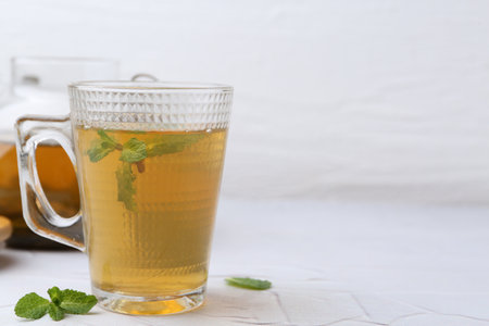 Aromatic mint tea and fresh leaves on white textured table, closeup. Space for textの写真素材