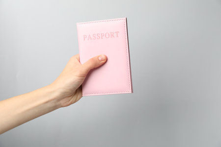 Woman holding passport in bright cover on grey background, closeupの写真素材