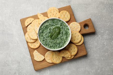 Delicious spinach sauce served with crackers on grey table, top viewの写真素材