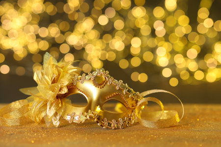 Beautiful carnival mask on golden shiny surface against blurred lightsの写真素材