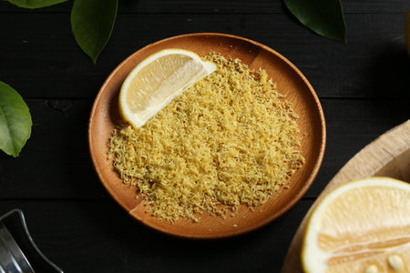 Lemon zest with fresh fruit slice on black wooden table, closeup