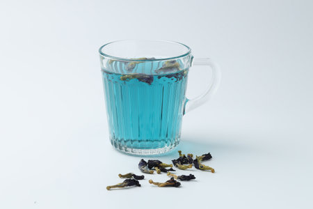 Fresh butterfly pea flower tea in cup and dry petals on white table, closeupの写真素材