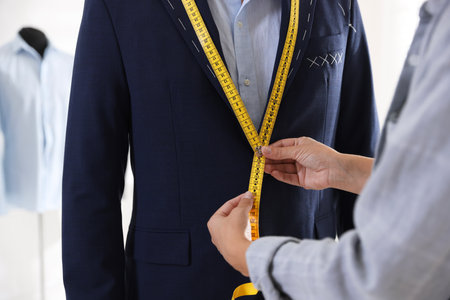Tailor measuring jacket on man during fitting in atelier, closeupの写真素材