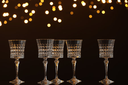 Empty wineglasses on mirror surface against dark background with blurred lights. Bokeh effectの写真素材