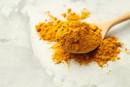 Turmeric powder and spoon on light gray table, closeup. Space for textの写真素材